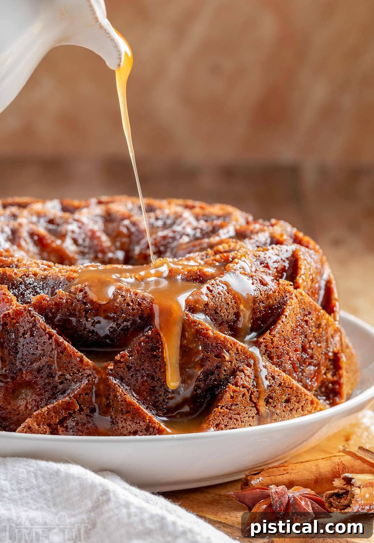 Luscious caramel glaze being generously drizzled over the intricate top of a baked apple bundt cake, highlighting its golden-brown surface.