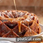 Caramel glaze being drizzled on top of the apple bundt cake.