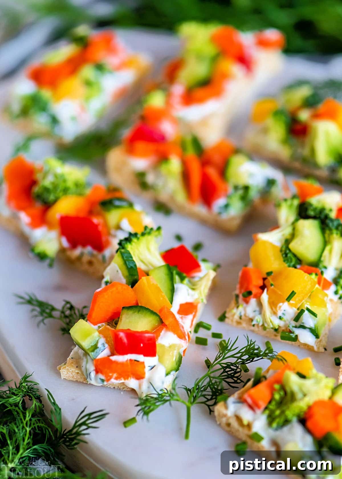 Vibrant veggie pizza cut into neat rectangles, artfully arranged on a marble board and garnished with fresh sprigs of fragrant dill, ready to be served as an appetizer.