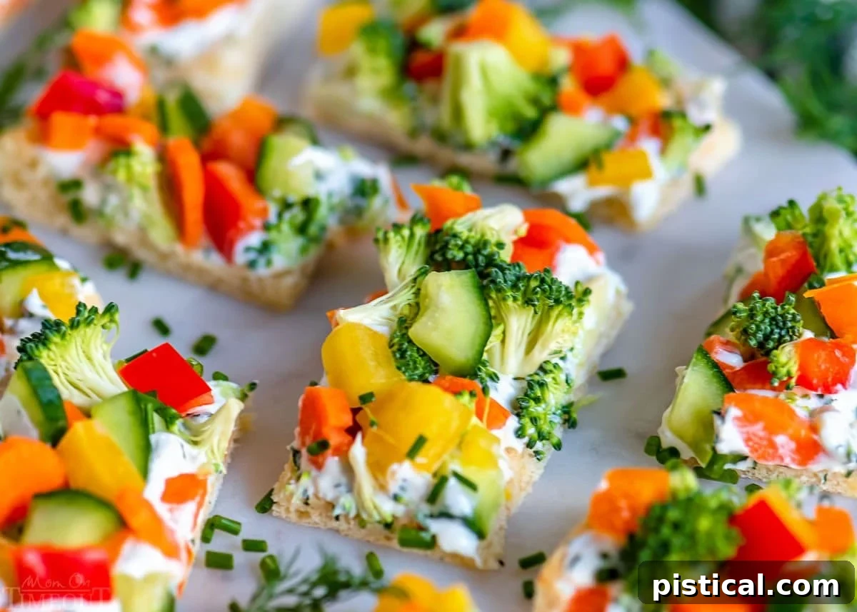 A close-up view of the delicious veggie pizza, precisely cut into small, appetizer-sized rectangles and neatly arranged on an elegant marble serving board, showcasing its vibrant colors and fresh appeal.