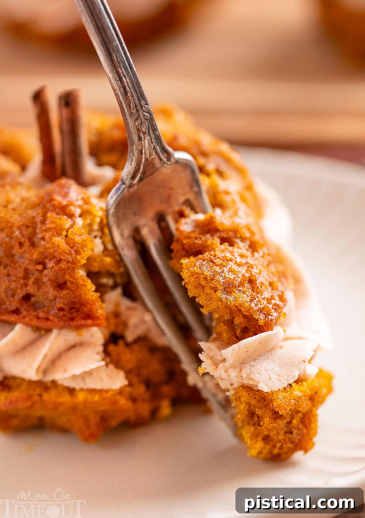 Forkful of pumpkin bundt cake being removed from the cake. Tender, moist cake and creamy frosting are shown on the fork.