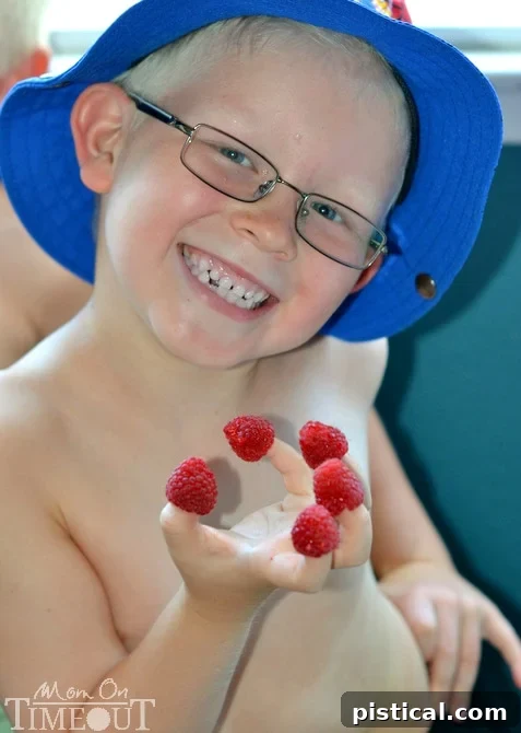 Two hands with raspberries on fingertips, showcasing the playful joy of eating berries.