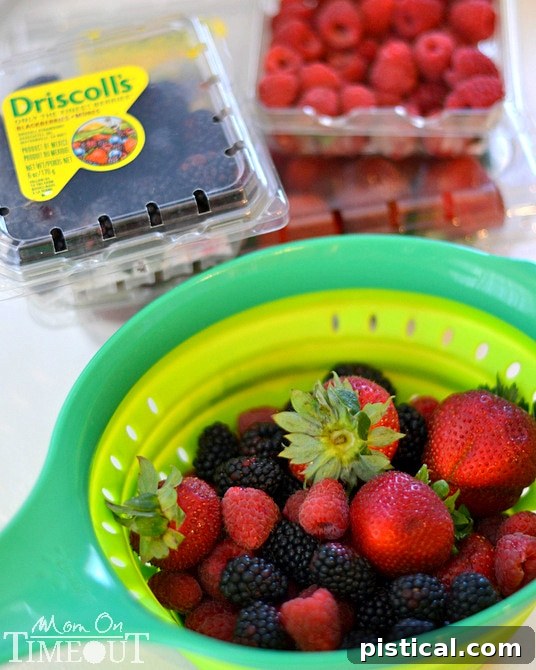 A colorful assortment of fresh Driscoll's berries, including strawberries, blueberries, raspberries, and blackberries.