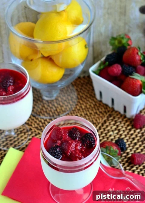 Close-up of a beautifully set Lemon Panna Cotta in a glass, generously topped with mixed berry compote, ready to be enjoyed.