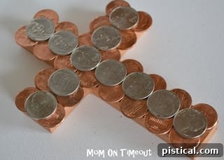 Close-up of coins being glued onto the cross, showing partial coverage and application technique