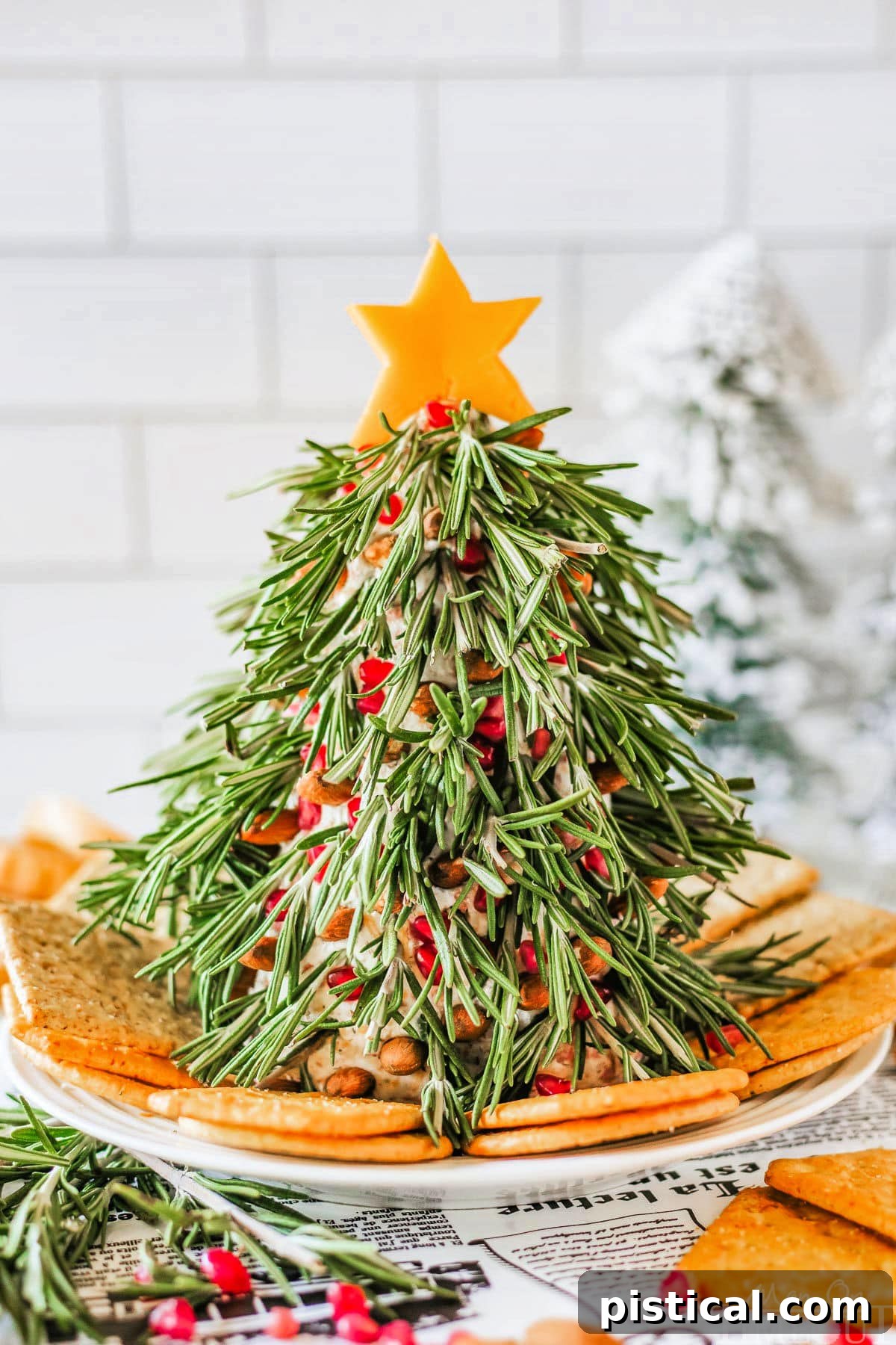 Festive Christmas Tree Cheese Ball with cheddar star and rosemary on a platter with crackers.