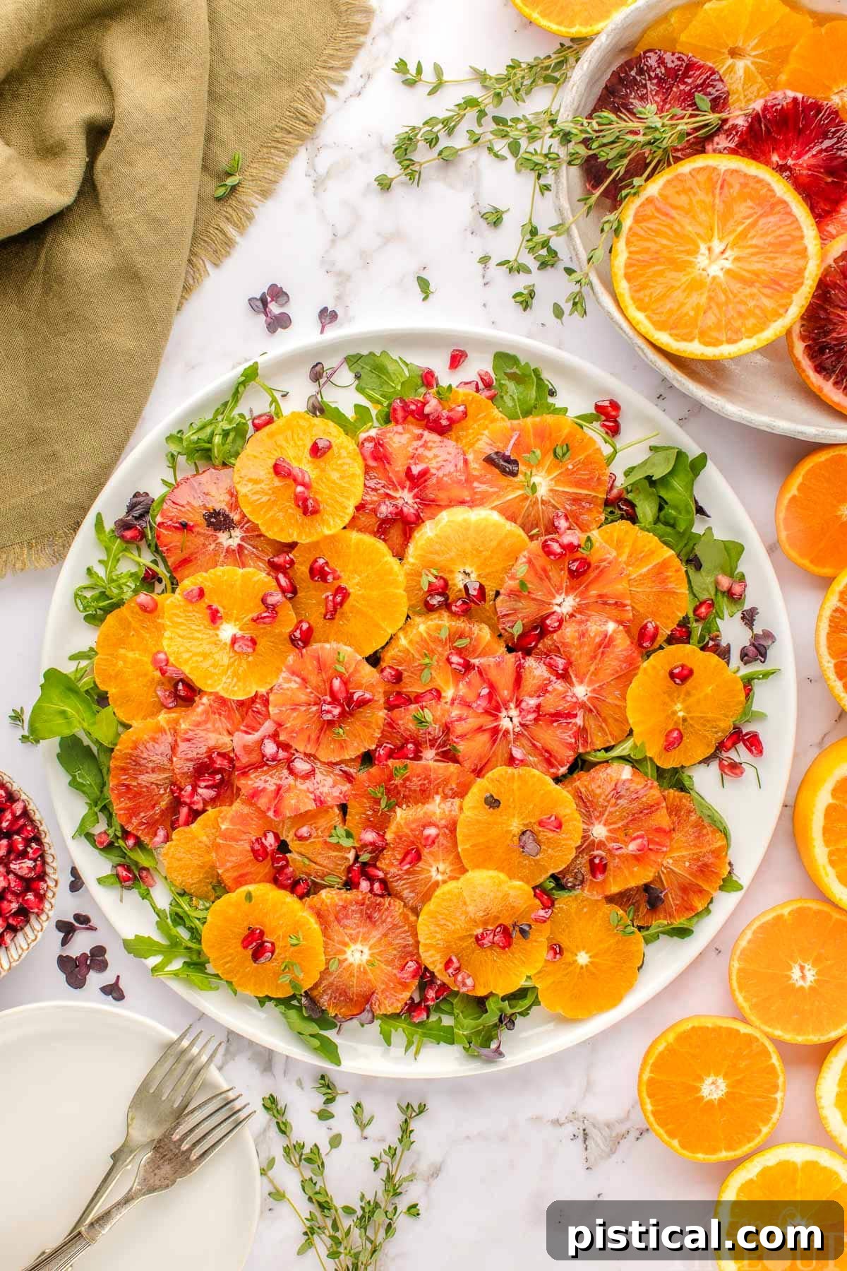 Top down view of vibrant citrus salad made with blood oranges, oranges, arugula and thyme and dressed with a citrus salad dressing.