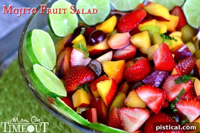 Close-up of Mojito Fruit Salad in a bowl, showing a variety of colorful fruits like strawberries, blueberries, kiwi, and plums, garnished with fresh mint.