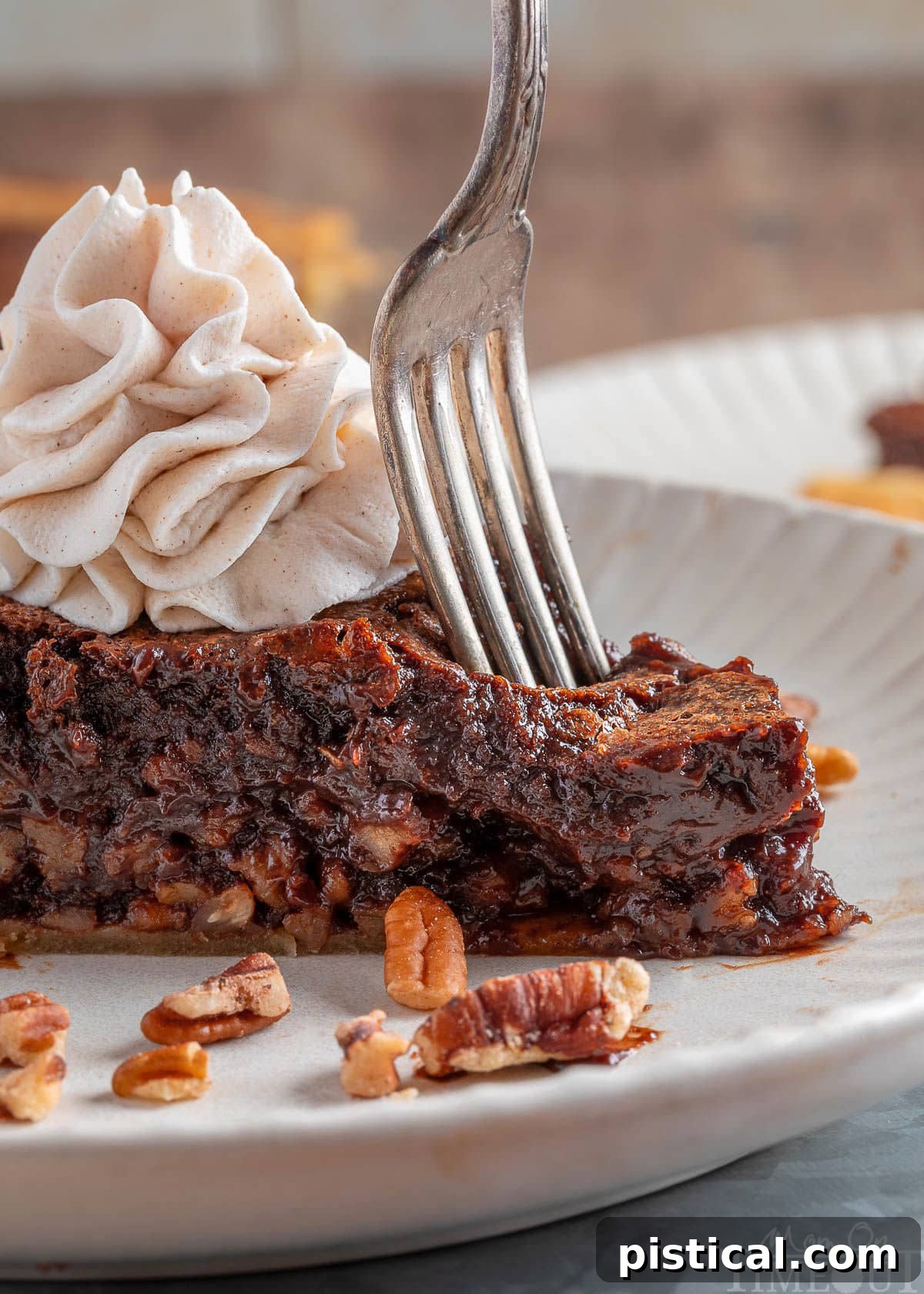 A fork gently cuts into the end of a slice of Bourbon Chocolate Pecan Pie, resting on a pristine white plate, showcasing the luscious filling and nutty texture.