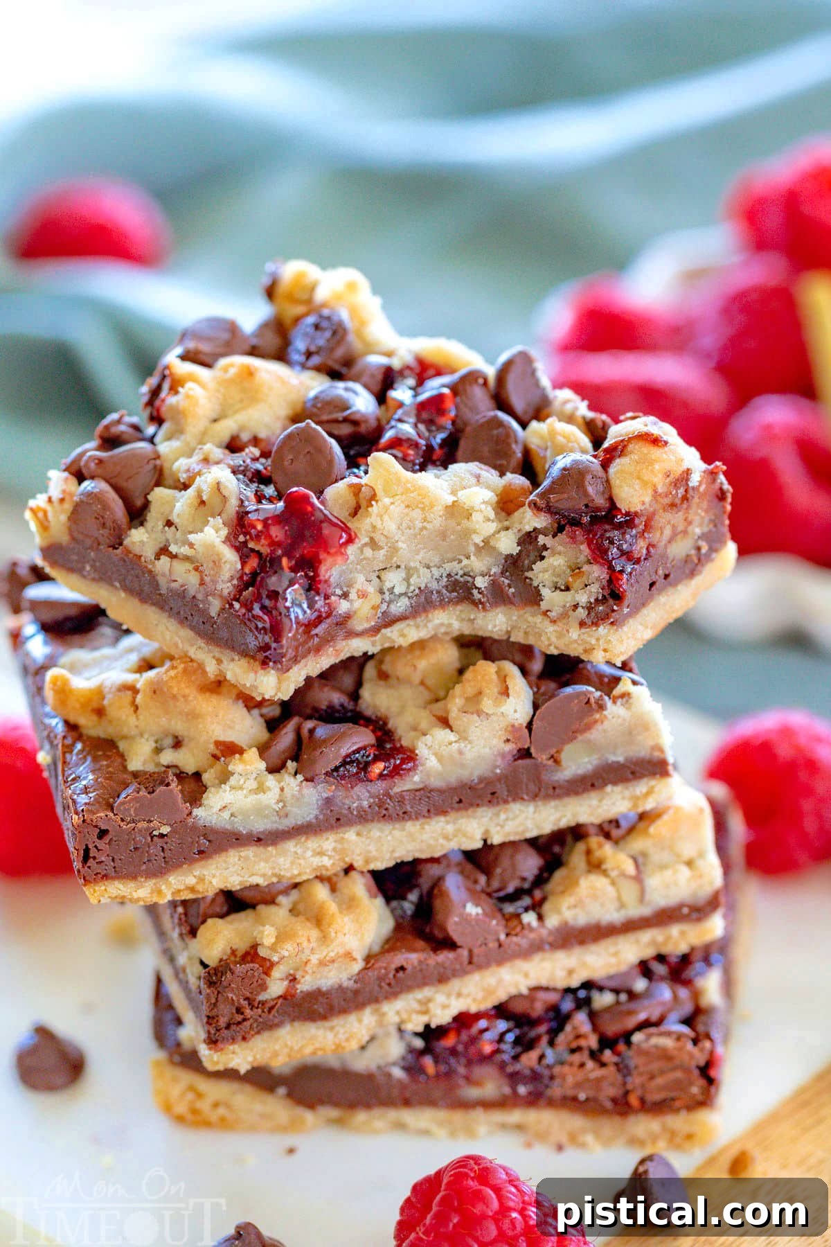 Four beautifully stacked chocolate raspberry crumble bars on a small marble board, with fresh raspberries scattered in the background, inviting a delicious bite.