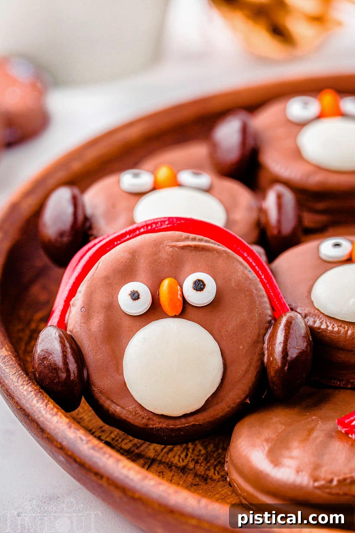 OREO Penguin propped up on a wood tray next to more penguin cookies. Penguin has red earmuffs.