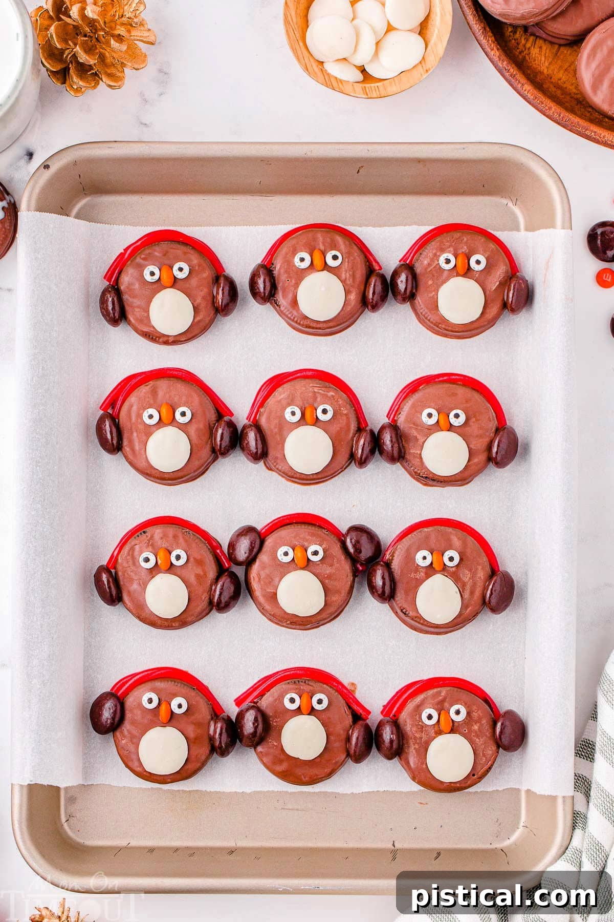 Twelve penguin OREOs on a baking sheet lined with parchment paper.