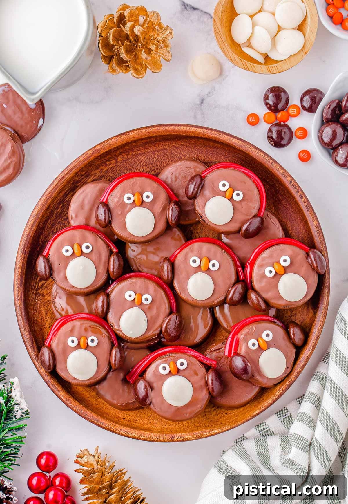 Top down shot of oreo penguins in a large round wood tray. Each penguin is decorated with red candy earmuffs.