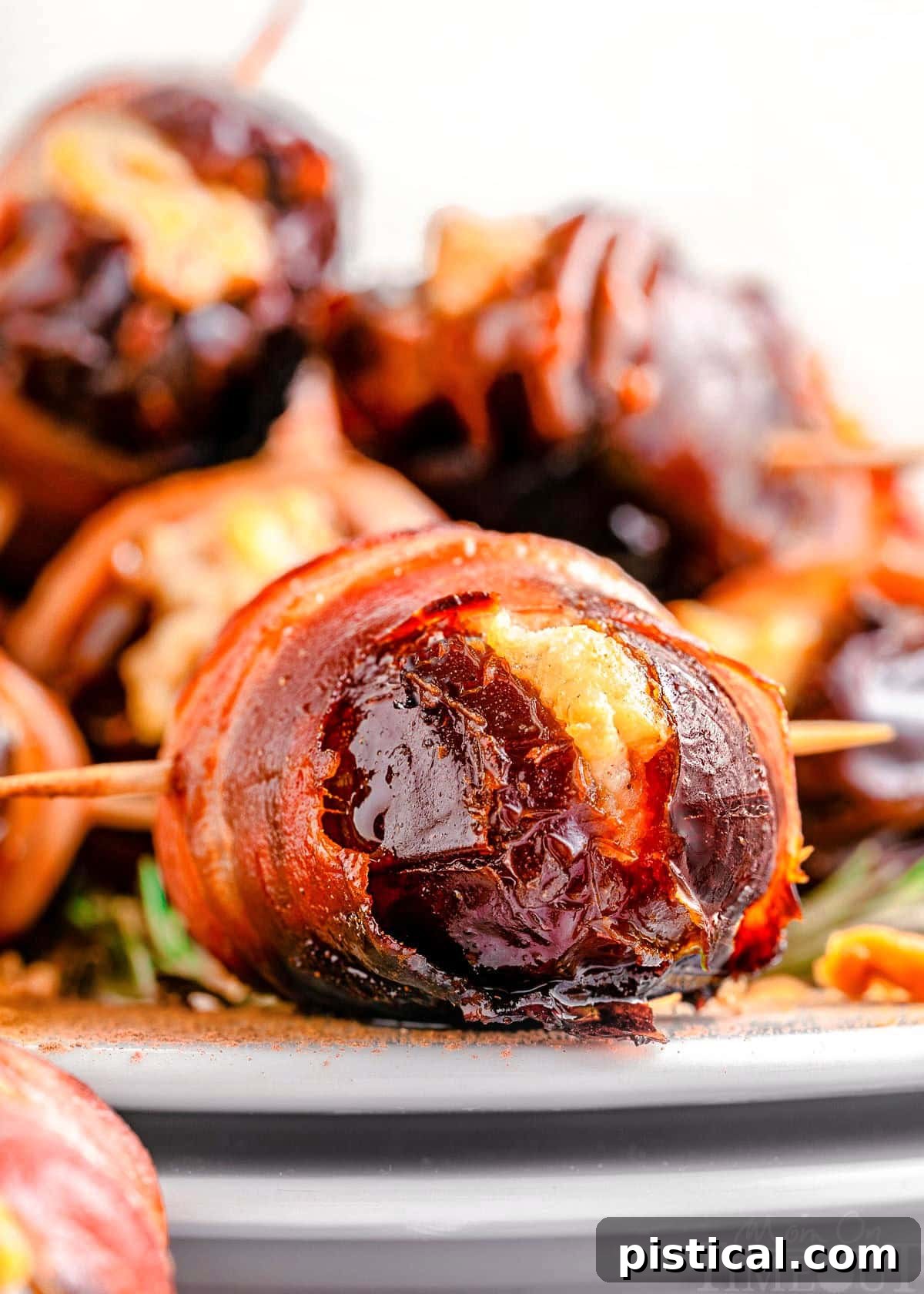 Bacon wrapped dates on white plate ready to be served.