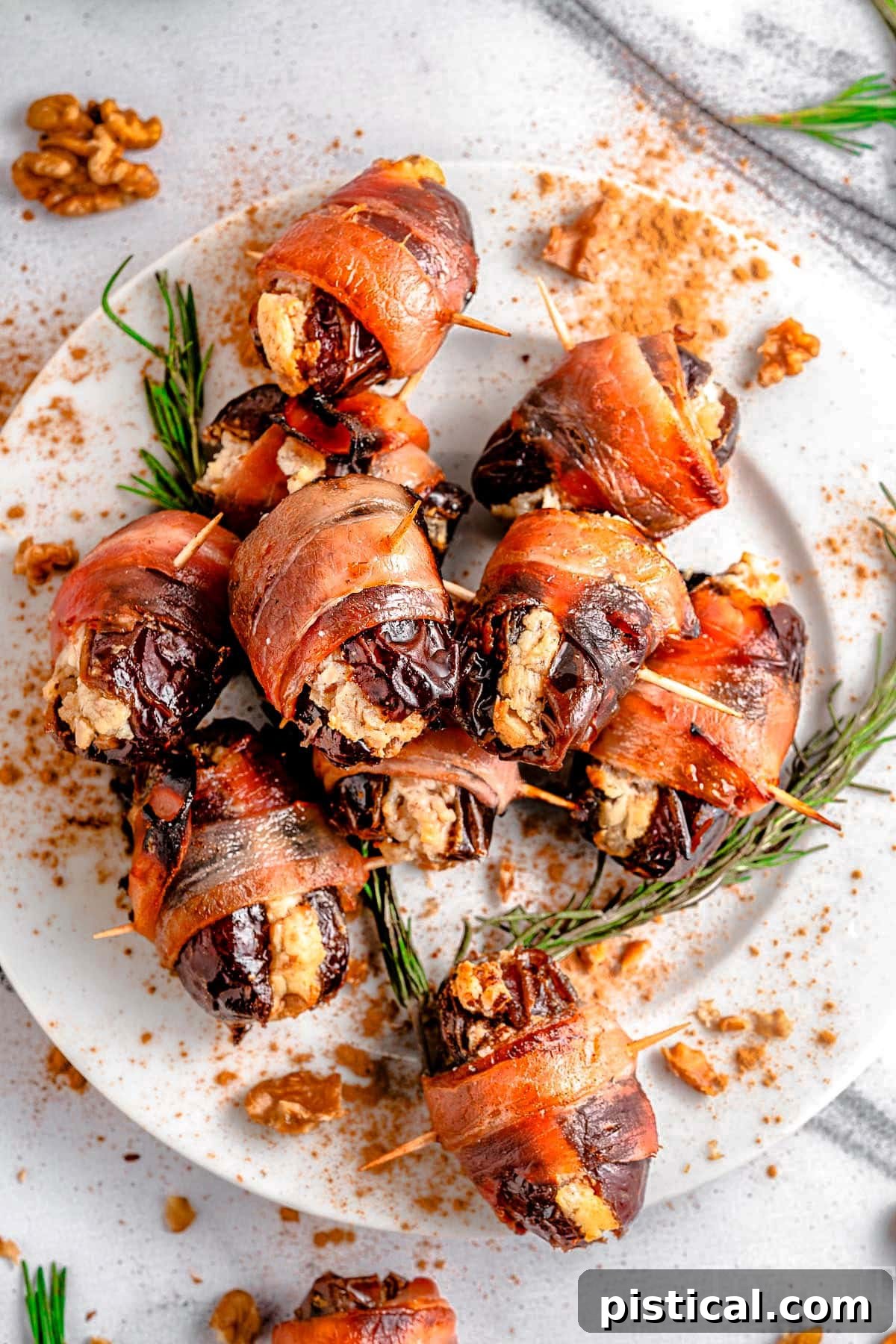 Top down view of plate of bacon wrapped dates garnished with rosemary.