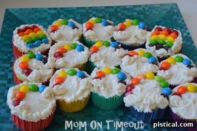 Another perspective of a rainbow cupcake, highlighting the colorful Skittles and white frosting