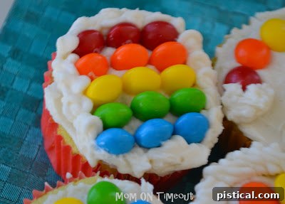 A close-up of a rainbow cupcake, showcasing the neat arrangement of Skittles and marshmallow clouds