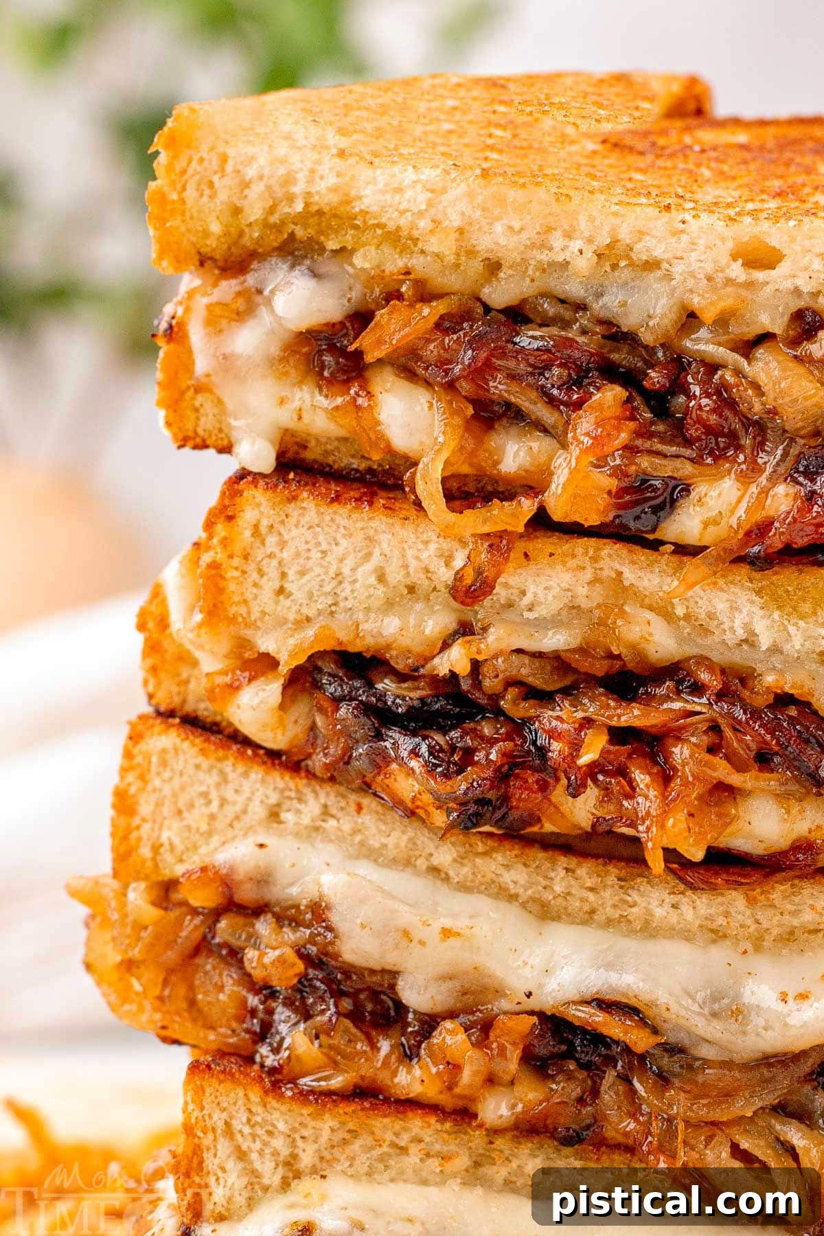 Close up look at caramelized onion grilled cheese cut in halve and stacked four high.