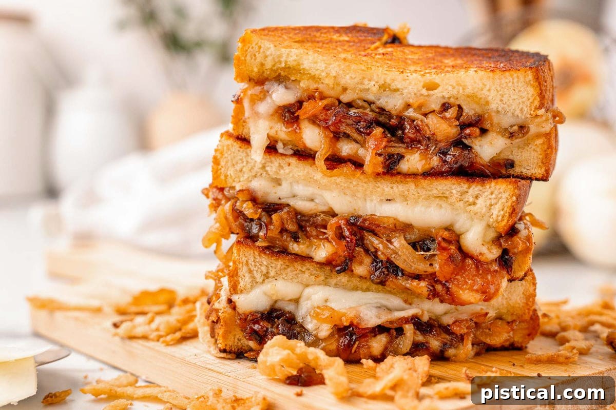 Wide shot of three halves of a french onion grilled cheese sandwich stacked on a wood cutting board with french fried onions surrounding it.