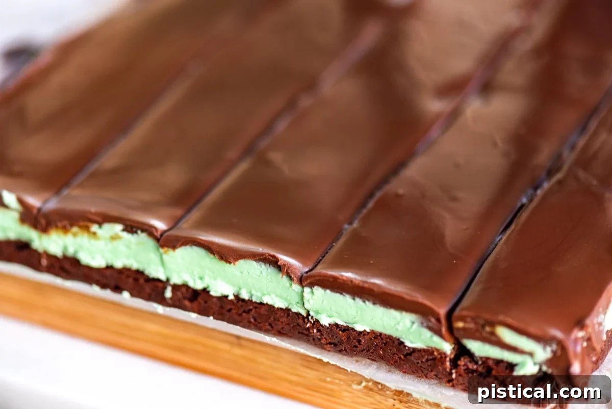 A wide shot of mint brownies on a cutting board, clearly showing the distinct three layers in cross-section.