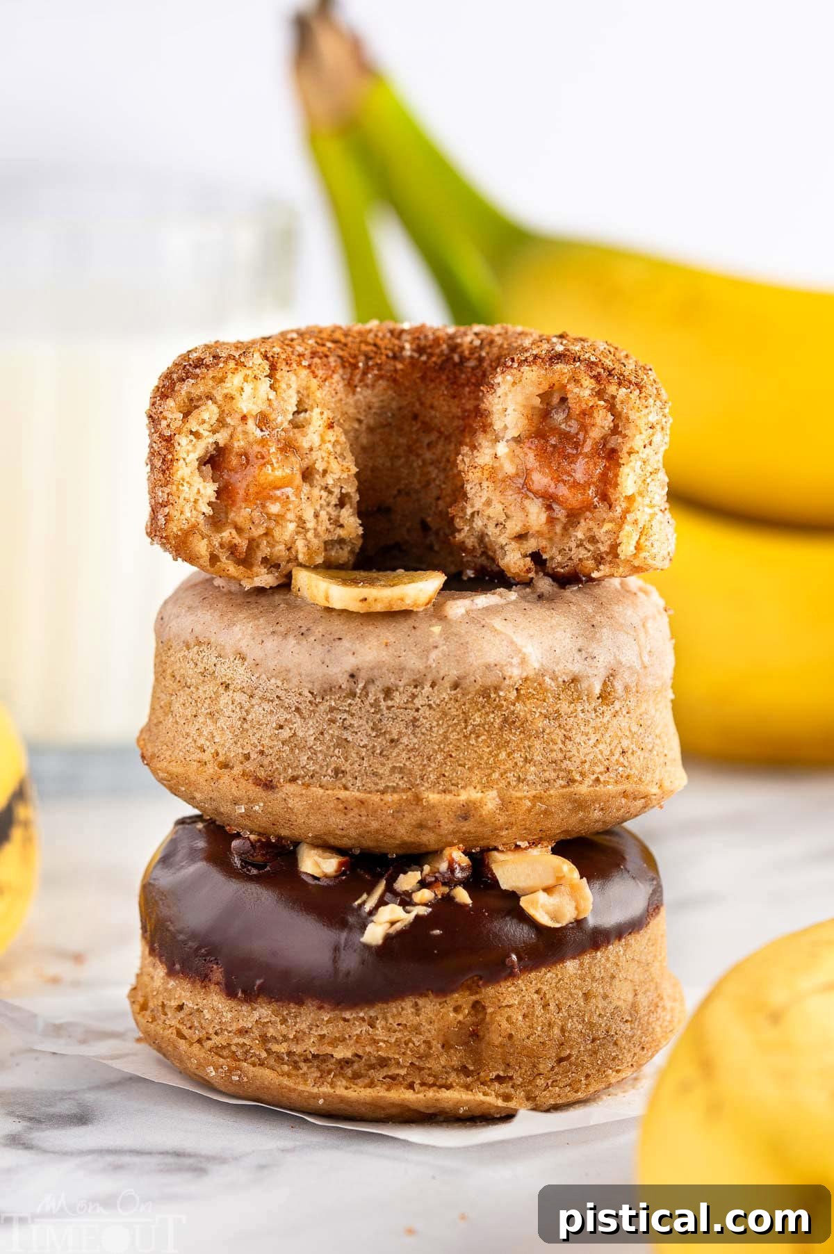 Delightful Banana Doughnuts 3 A stack of golden brown baked banana donuts on a white plate, with fresh bananas in the background, highlighting the key ingredient.