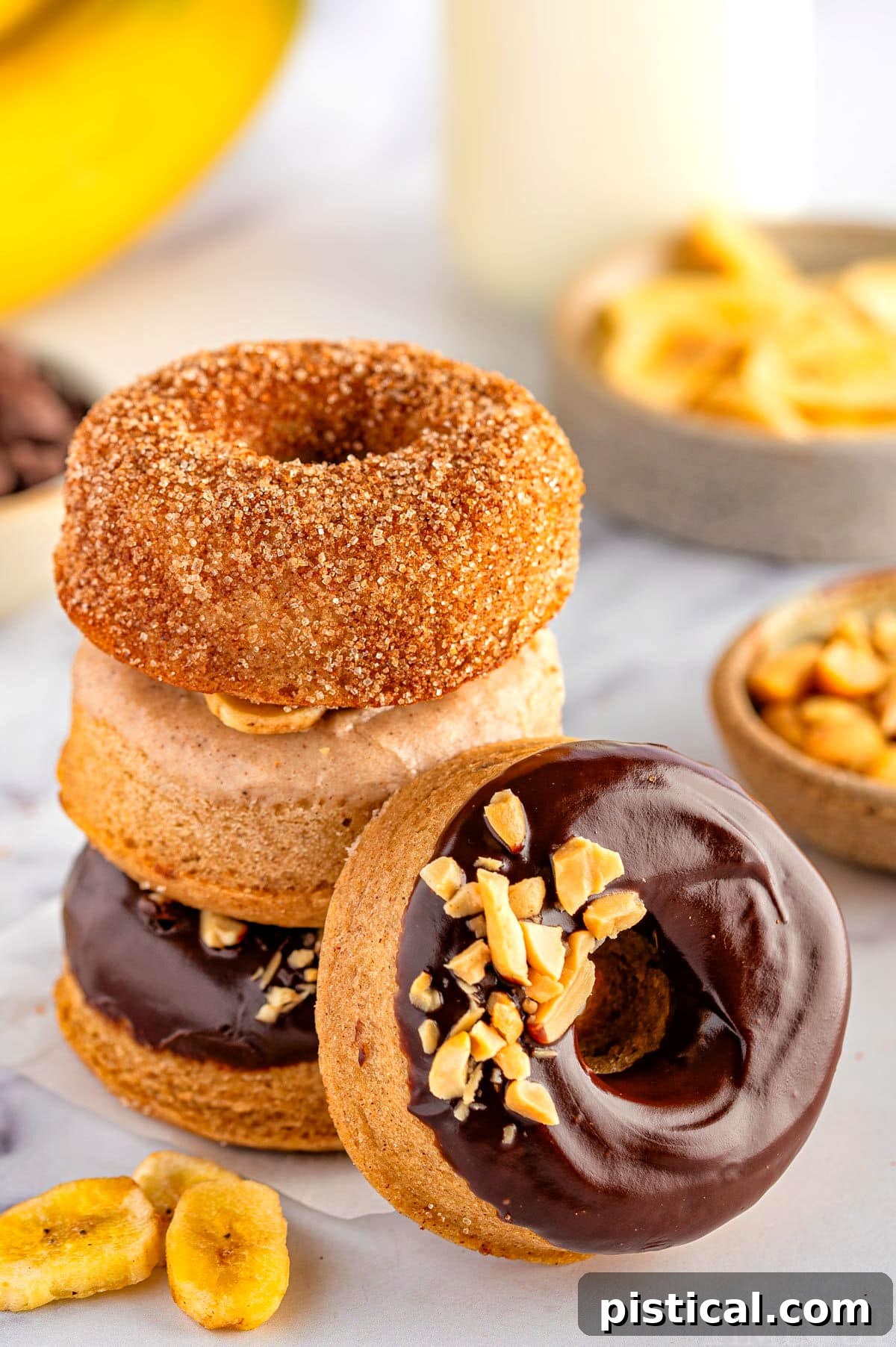 Delightful Banana Doughnuts 8 A beautiful stack of banana donuts, with one chocolate-glazed donut artfully leaning against the pile, showcasing the appealing variety.