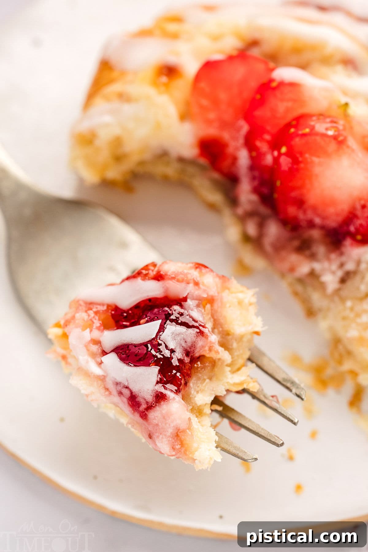 A single strawberry danish pastry on a white plate with a forkful already taken, highlighting its flaky layers and creamy filling, inviting a taste.