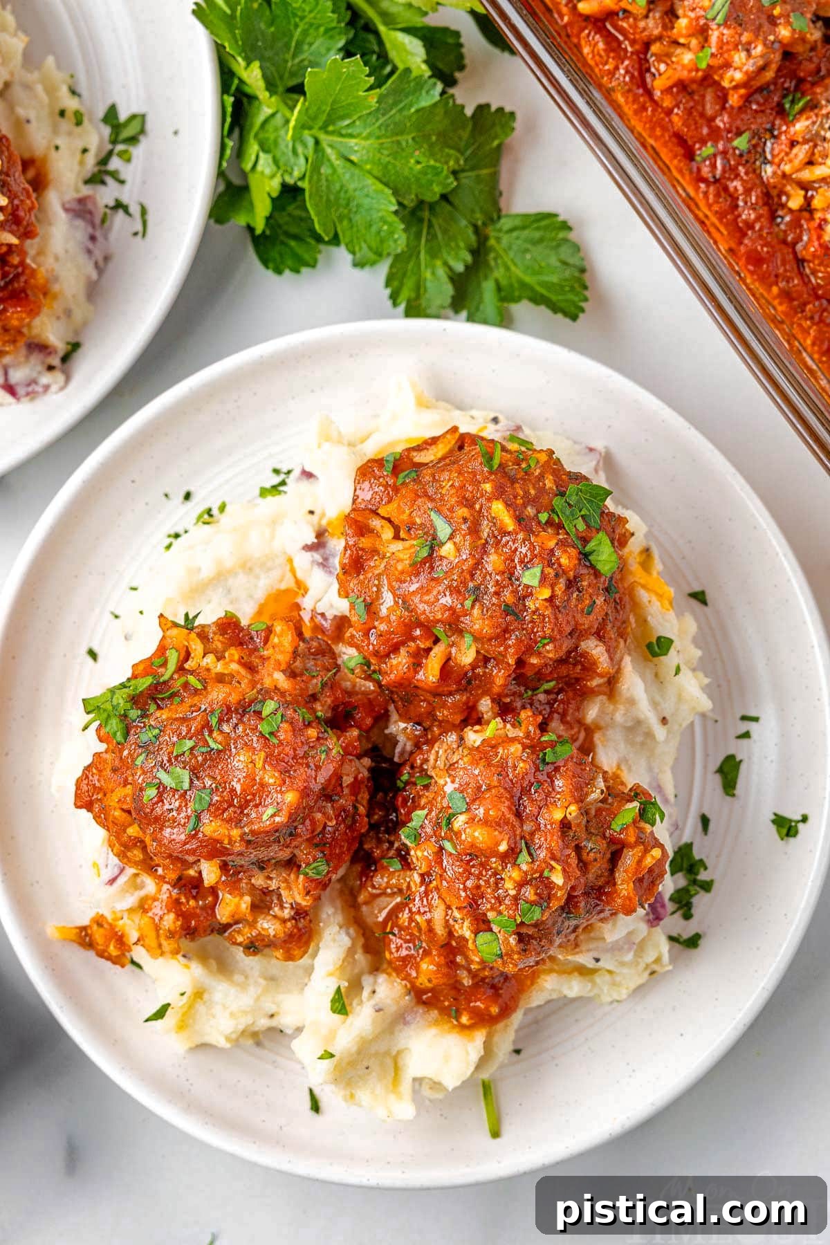 Three porcupine meatballs on a round white plate topped with fresh parsley, showcasing their signature texture.