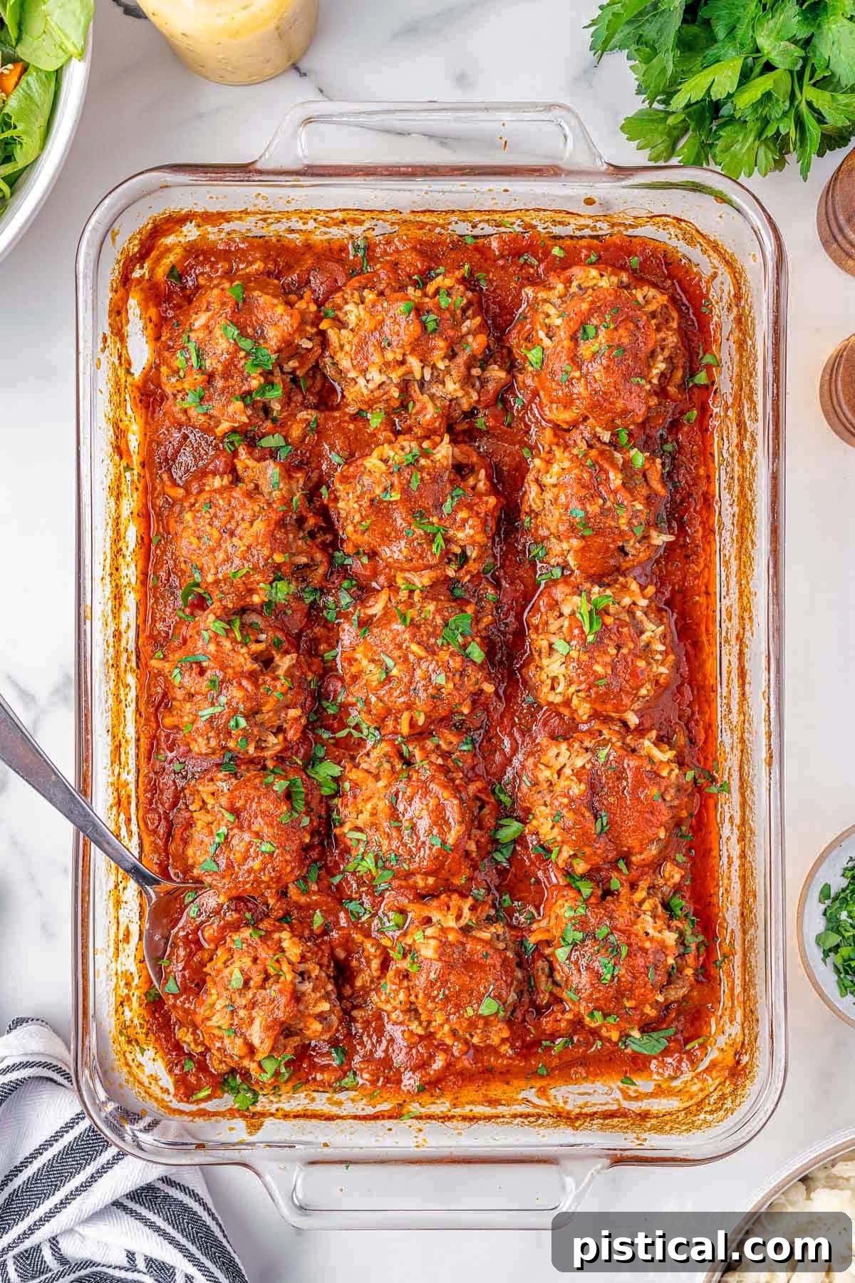Porcupine Meatballs, sprinkled with fresh parsley, arranged neatly in a baking pan, surrounded by key ingredients on a wooden surface.