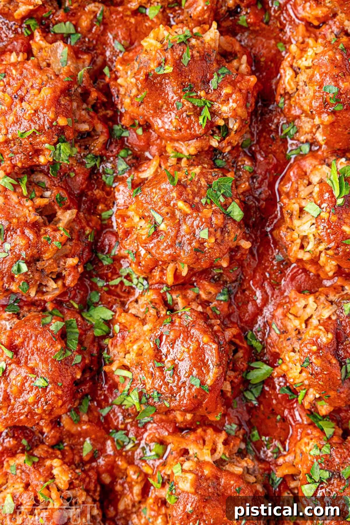 Close-up of baked Porcupine Meatballs, perfectly lined in a baking pan, generously sprinkled with fresh parsley.