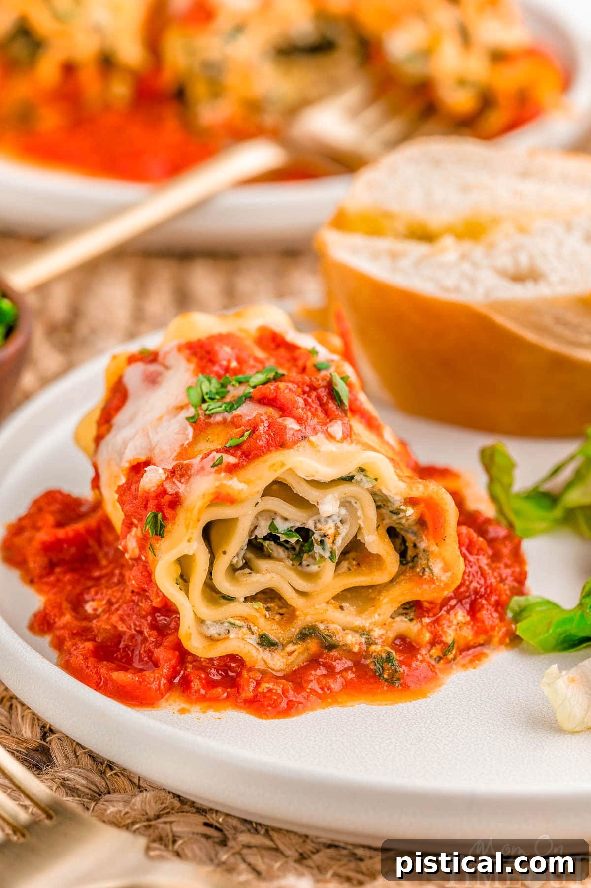 Lasagna Roll Ups plated with salad and bread on a dinner plate.