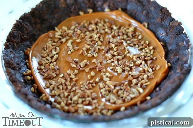 Layered Brownie Sundae Pie: A Crowd-Pleasing Dessert Close-up of a slice of Brownie Sundae Pie, showing its distinct layers of brownie, caramel, nuts, and chocolate pudding.