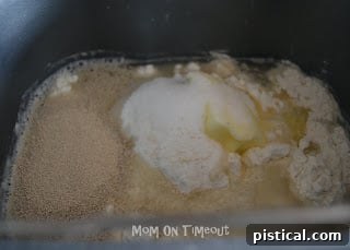 Ingredients being added to a bread machine pan for pizza dough. Shows the initial setup for bread machine pizza dough.