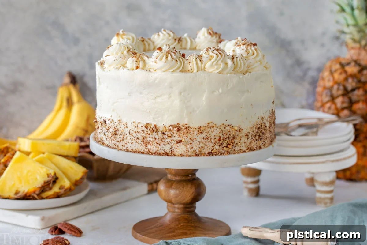 A complete, stunning Hummingbird Cake presented on an elegant marble cake stand, set against a backdrop of fresh bananas and pineapples, hinting at its tropical essence. Small, delicate plates are subtly visible in the background, awaiting slices of this delightful dessert.