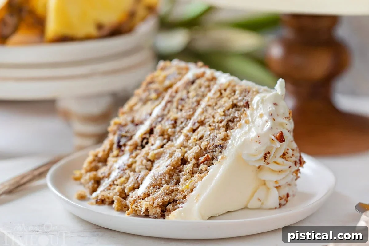 A beautifully presented slice of Hummingbird Cake, turned on its side to reveal its moist layers and generous cream cheese frosting, resting elegantly on a pristine round white plate.