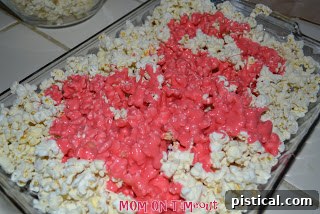 Sweetheart Popcorn Bites 7 Drizzling warm marshmallow mixture over popped popcorn in a baking dish.