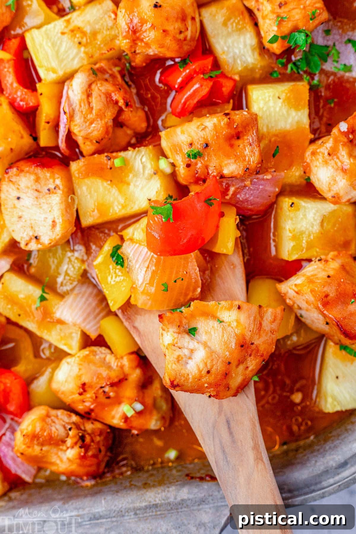 Pineapple Glazed Island Chicken 7 Hawaiian chicken on sheet pan with a wooden spoon scooping up chicken and pineapple, ready to serve.