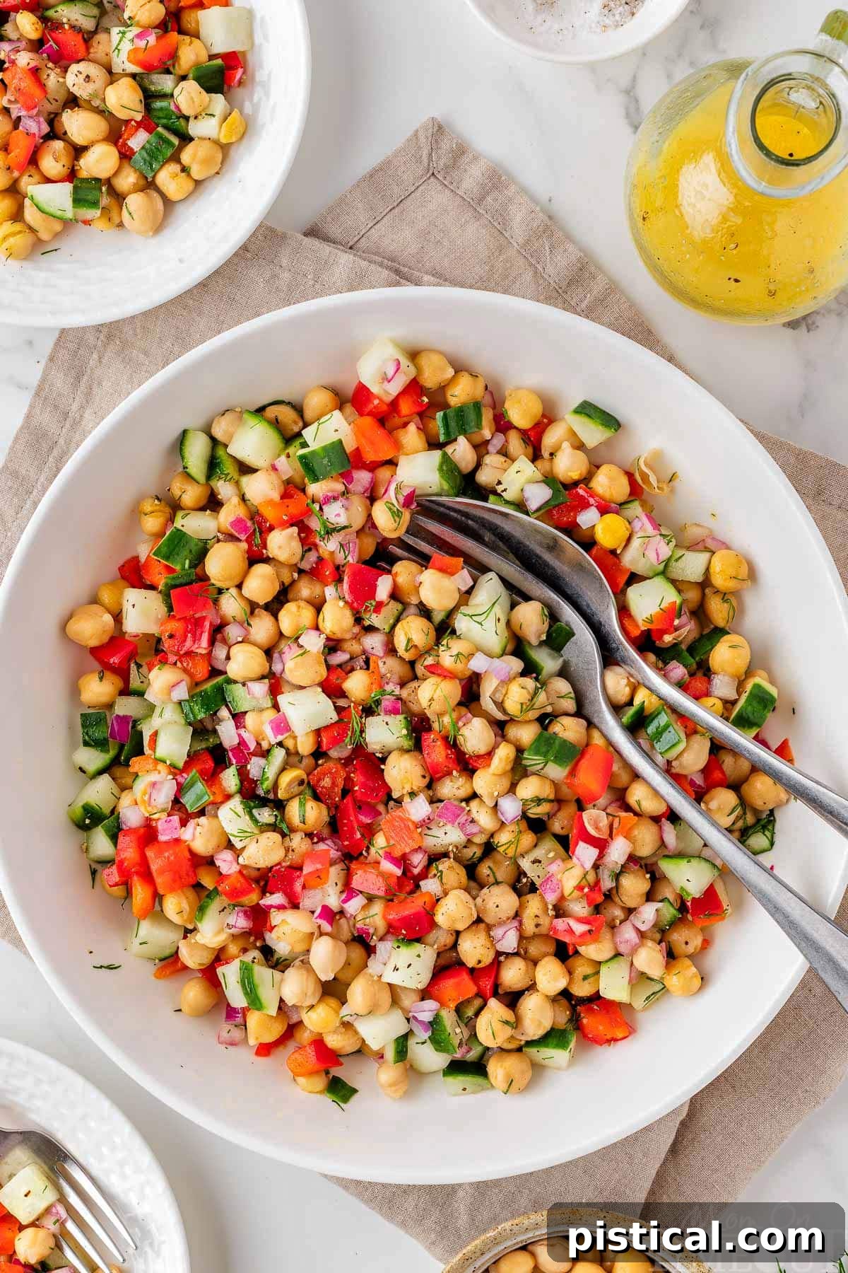 Overhead view of white bowl of chickpea salad made with cucumbers and tossed with a vinaigrette.