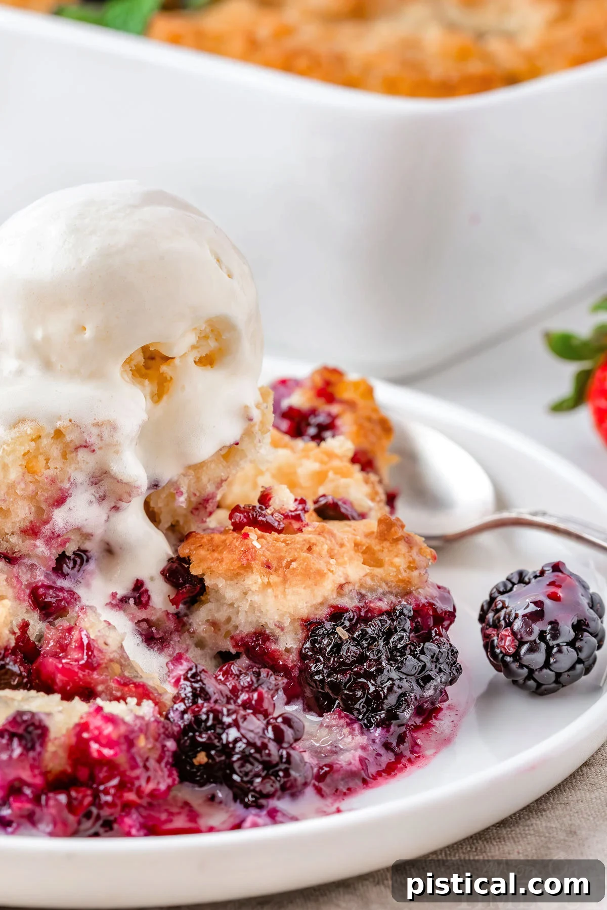 Rustic Berry Bake 7 Easy Berry Cobbler recipe served on a white round plate with a scoop of vanilla ice cream and a spoon, ready to be enjoyed.