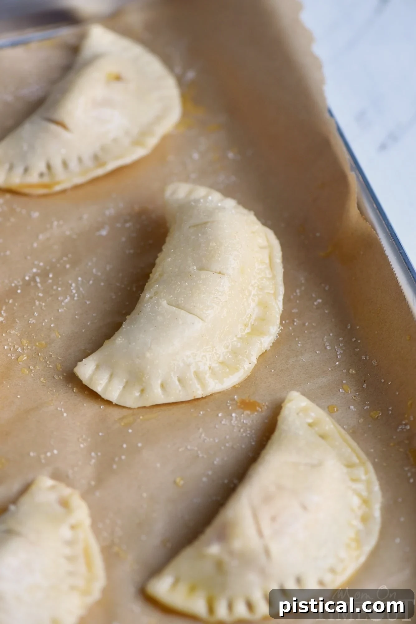 Unrolled pie dough lightly floured, showing circles cut out and ready for filling, symbolizing the start of empanada preparation.