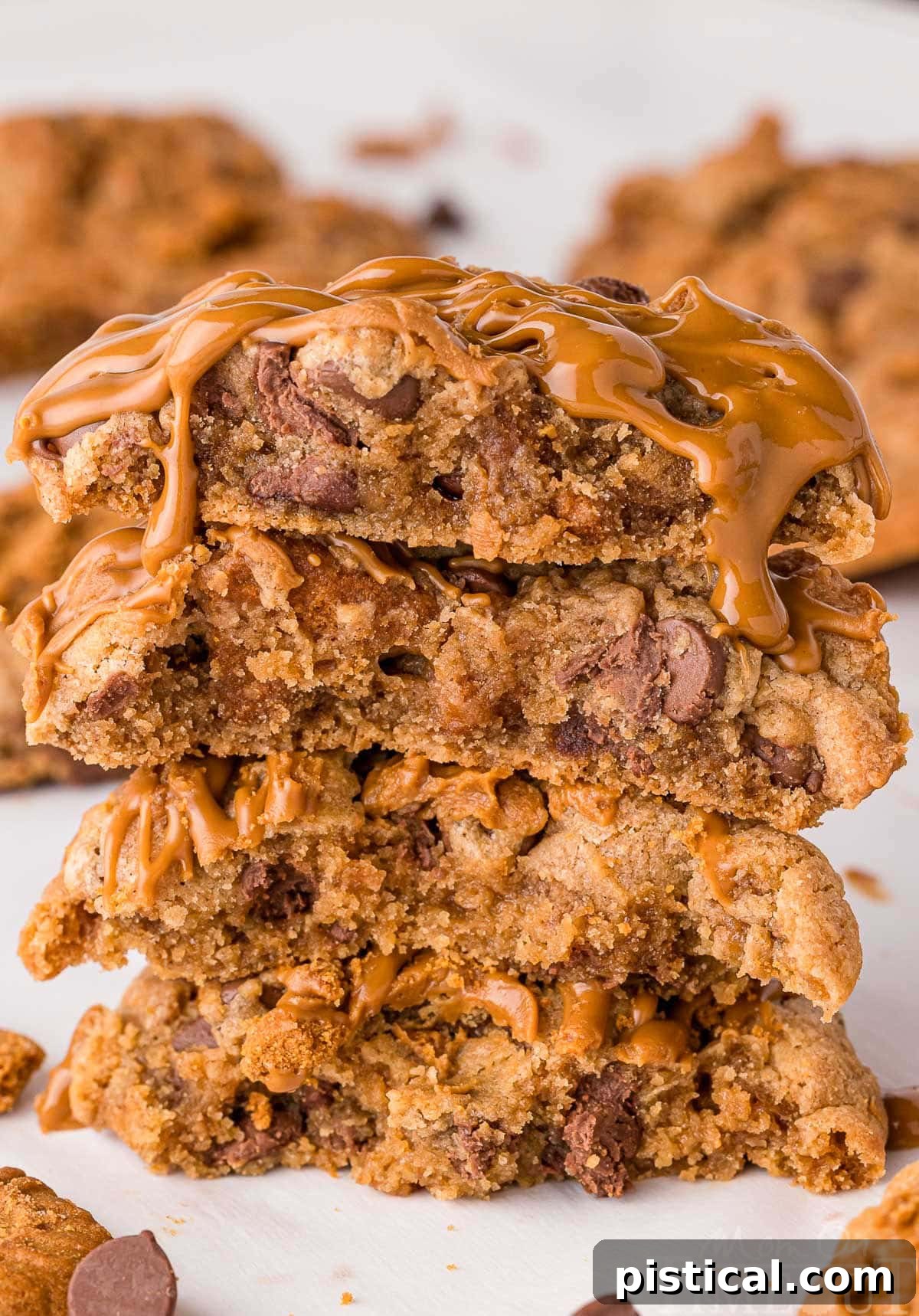 Ultimate Biscoff Chocolate Chip Cookies 3 Stack of four biscoff chocolate chip cookies topped with cookie butter stacked on white parchment.