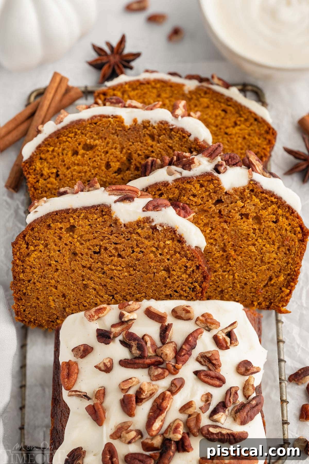 Overhead shot of pumpkin bread with cream cheese frosting on board with four slices cut and arranged on top of each other at an angle.
