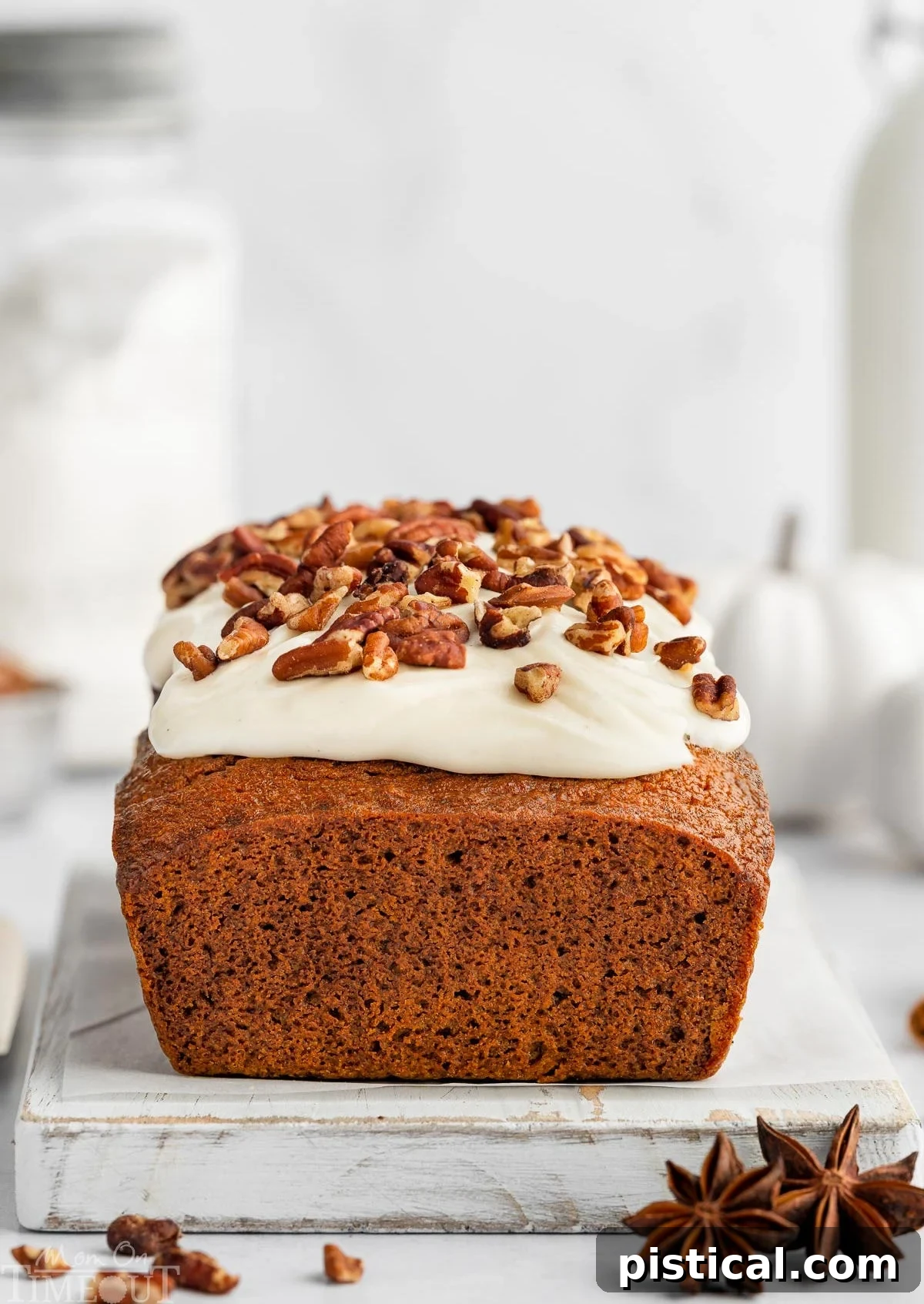whole pumpkin loaf with cream cheese frosting sitting on white cutting board.