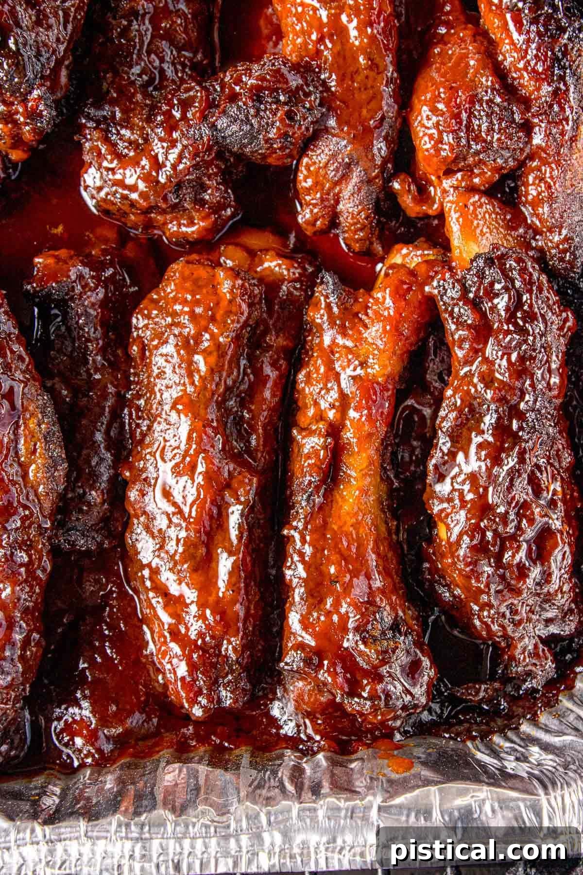 Close up overhead shot of party ribs in foil pan with shiny glaze.