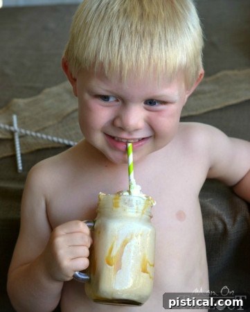 Young boy, Bryce, happily drinking a Caramel Apple Shake, whipped cream on his face. | MomOnTimeout.com