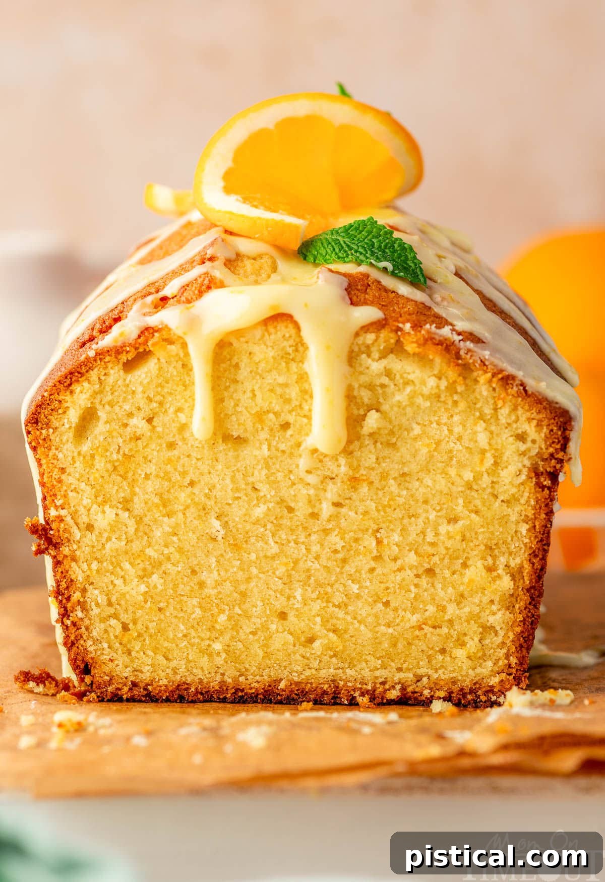Zesty Orange Pound Cake 2 Orange pound cake with end cut off sitting on wood board topped with a glaze.