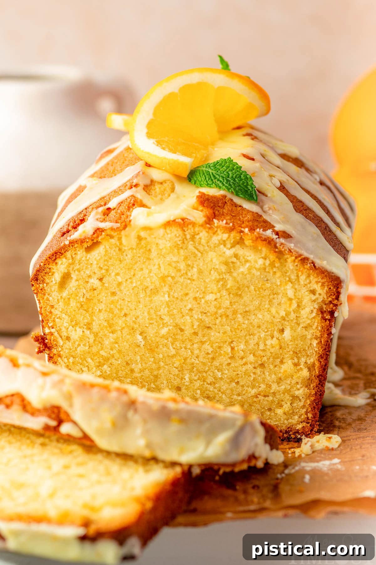 Zesty Orange Pound Cake 7 Front view of orange pound cake on wood cutting board with two slices cut off.