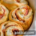 Chicken cordon bleu crescent rolls in white pie dish.
