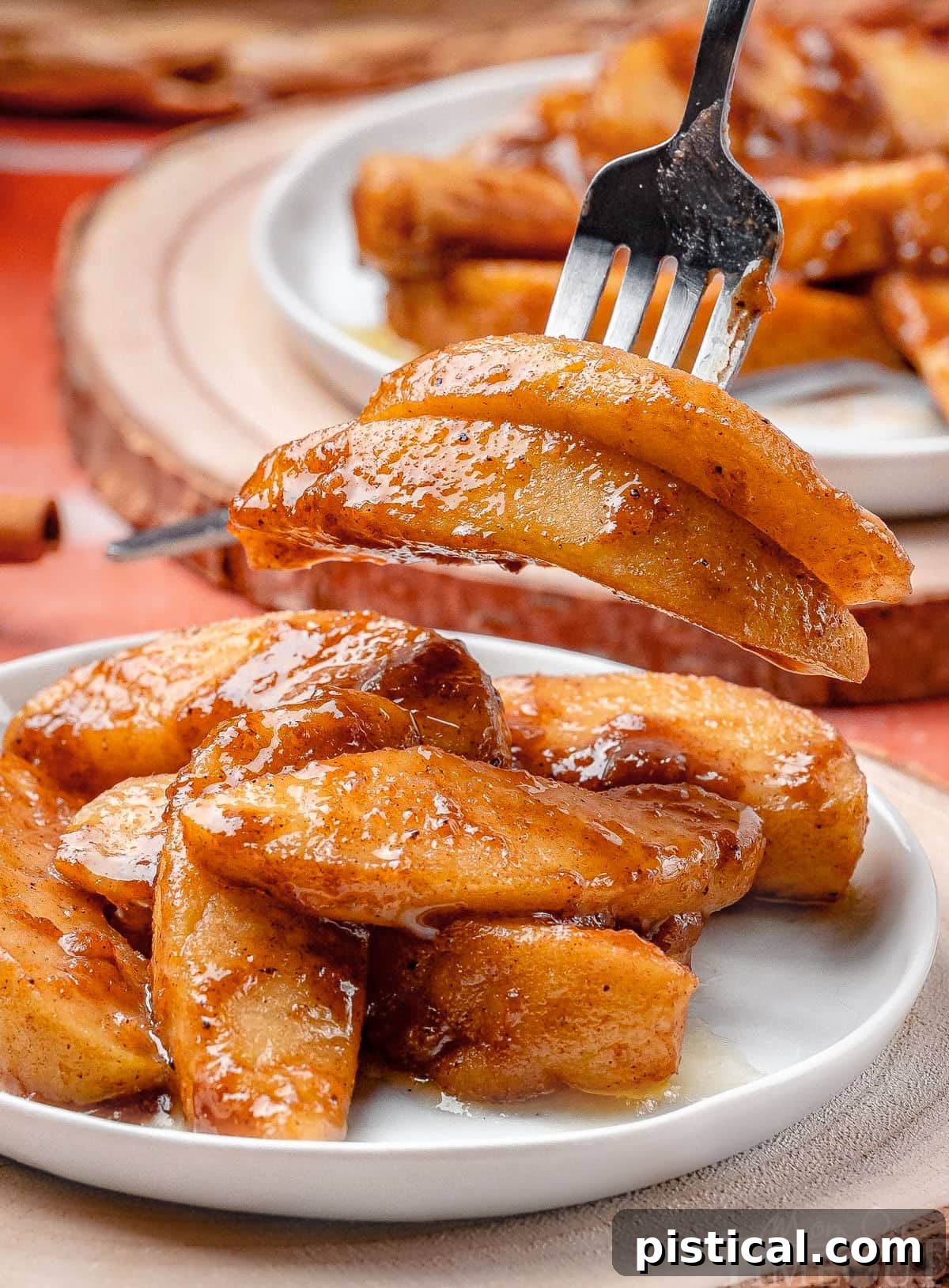 Recipe for fried apples shown plated with a fork lifting away two apple pieces.