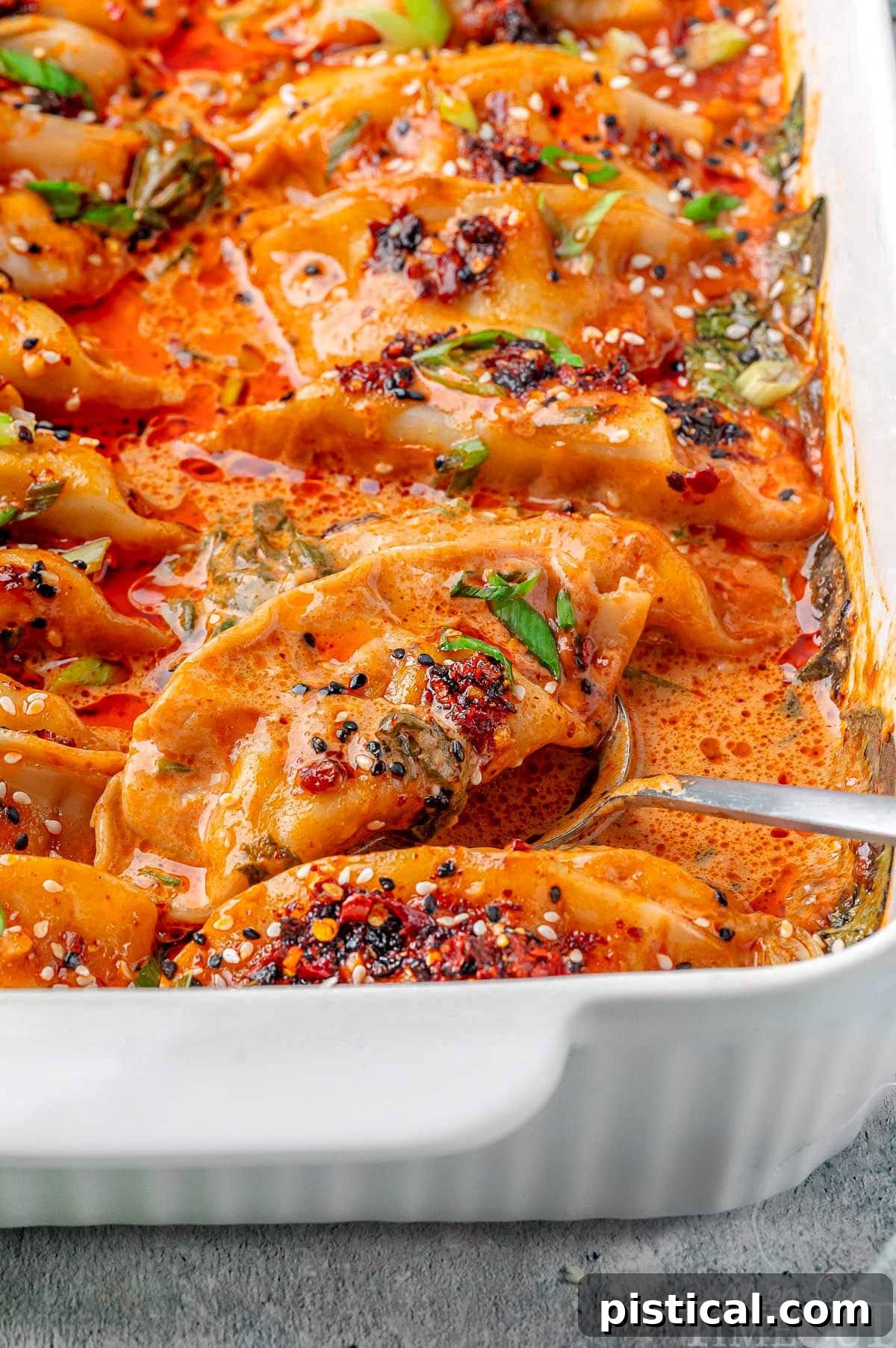 Crispy Sheet Pan Dumplings 4 A pristine white baking dish filled with freshly baked dumplings, steaming hot and ready to be garnished and served for a quick, delicious meal.